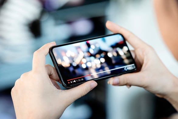 Person watching a video on a smartphone, part of a guide to content marketing through visual storytelling.