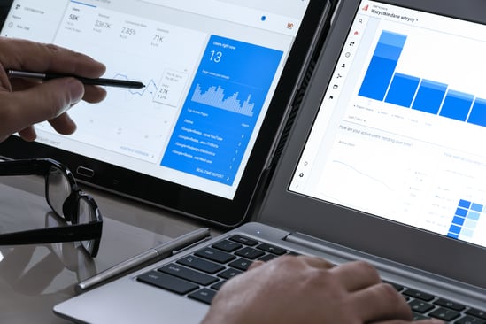 Analyzing marketing data on tablet and laptop to optimize AI-driven campaign performance.