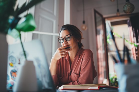 Young businesswoman thinking about something while sitting in front of an open laptop
