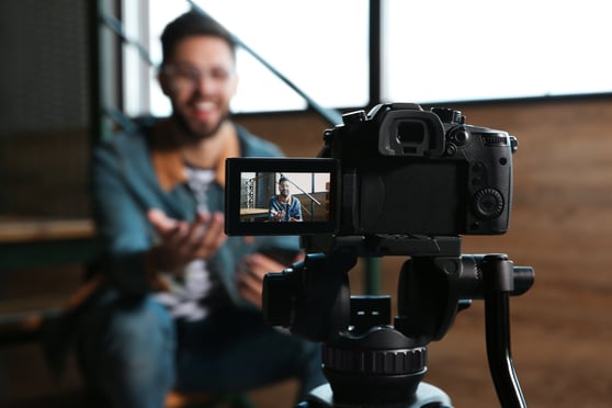 Blogger recording video indoors, focus on camera screen