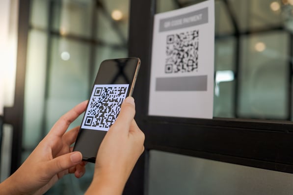 Person scanning a QR code on a display with a smartphone.