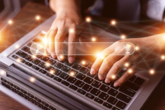 Hands typing on a laptop with search icons, showing the Google click crisis in online visibility.