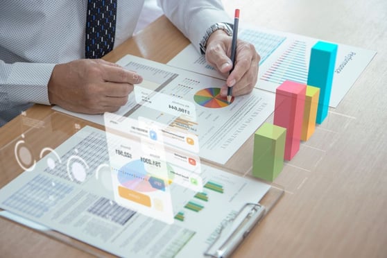 Businessman is holding a pencil while reviewing financial statements with augmented reality charts.