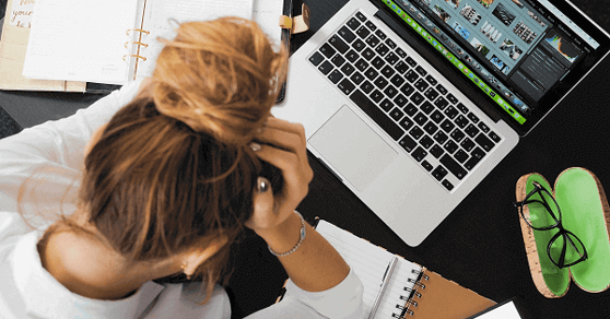 Woman holding her head in front of a open laptop.