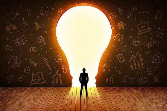 Person standing in front of a giant lightbulb.