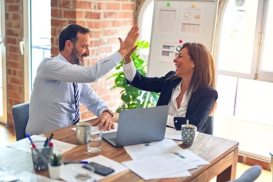 Two middle-aged aged business workers smiling happily and confidently, showing the power of CRM for businesses.